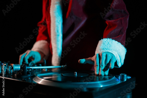 Hip hop dj in Santa outfit scratches vinyl record on turntable. Disc jockey plays music on Christmas party
