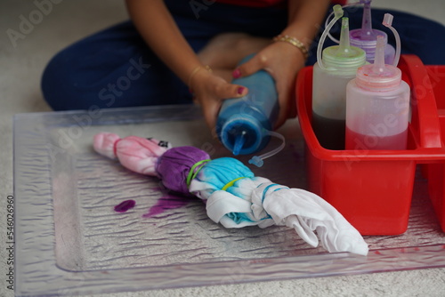 Little kid enjoying making a craft, using different colour ink to paint a tie-dyed cloth. Kids arts and crafts, Tie dye—art and craft DIY for children concept.