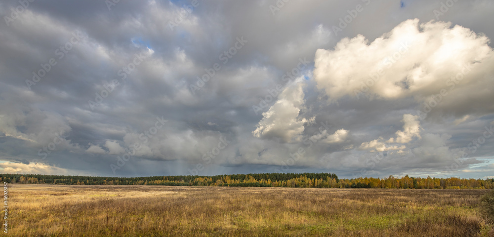 Dramatic sky over the horizon. Autumn landscape, the sun's rays illuminate the field and forest. Bright autumn evening. Dramatic sky over the horizon. Autumn landscape, the sun's rays illuminate the field and forest. Bright autumn evening.