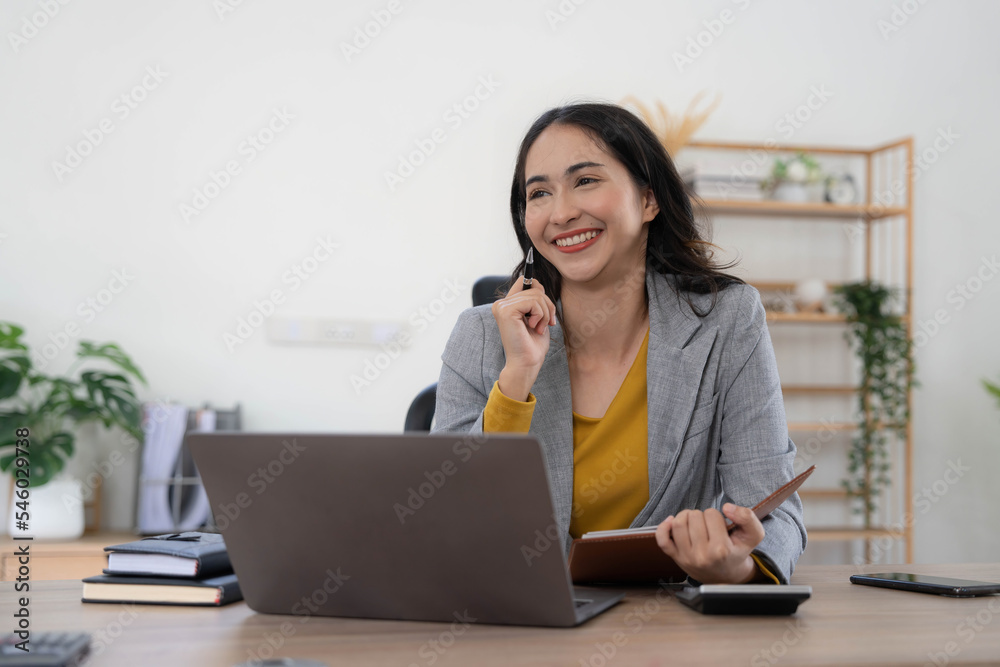 Portrait of an Asian young business Female working on a laptop computer in her workstation.Business people employee freelance online report marketing concept. Portrait of an Asian young business Female working on a laptop computer in her workstation.Business people employee freelance online report marketing concept.