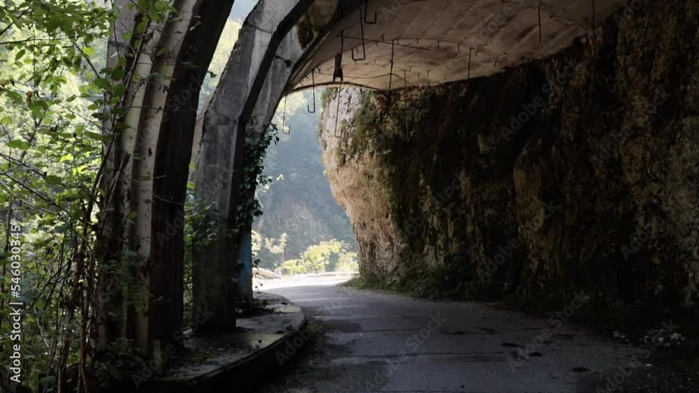 An old abandoned highway in the mountains. Collapses of rocks and trees, rockfalls on the road. Rocks, mountain gorge. Viaducts, open road tunnels. Damaged bumpers on the side of the road. An old abandoned highway in the mountains. Collapses of rocks and trees, rockfalls on the road. Rocks, mountain gorge. Viaducts, open road tunnels. Damaged bumpers on the side of the road.