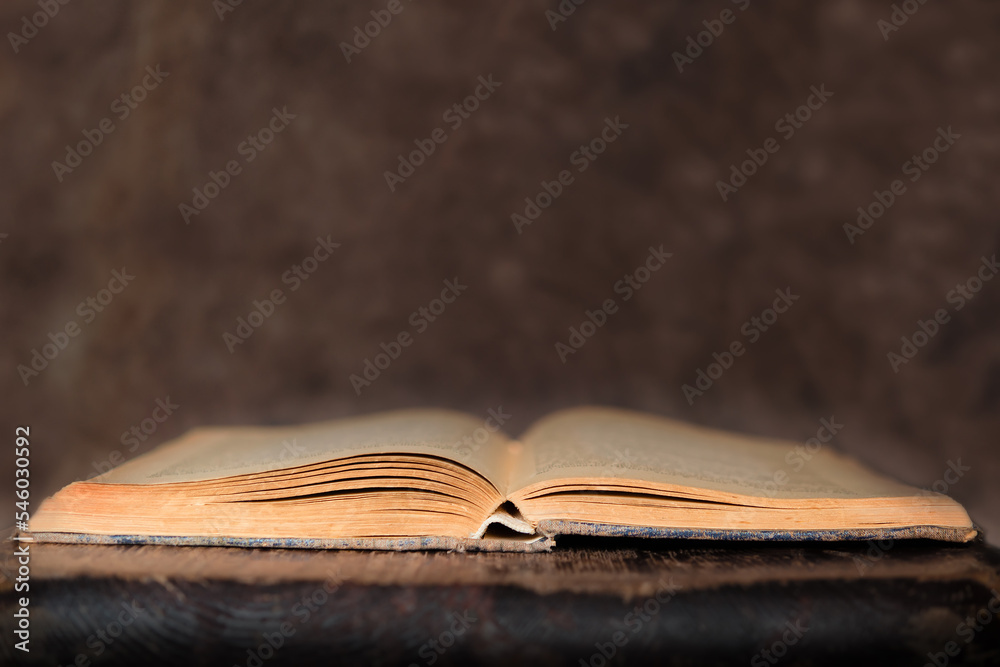 Obraz premium old book on wooden surface. background of a stack of a bible on an open library