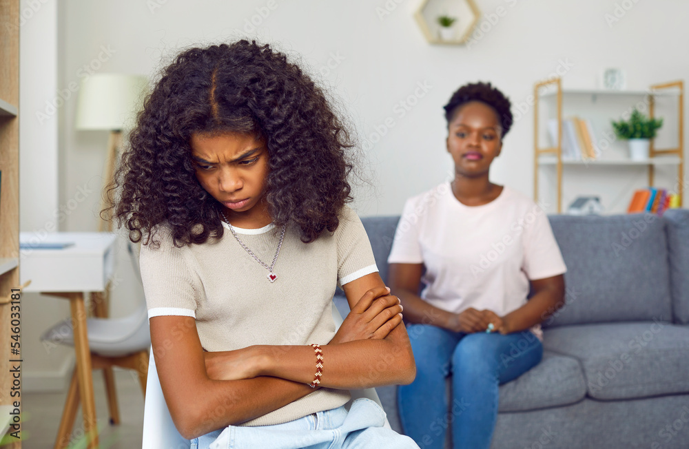 Unhappy, sad, stressed, depressed, antisocial diverse Afro American child girl sitting with arms crossed at psychologist's office. Kids, psychology, psychological problem, depression concept Unhappy, sad, stressed, depressed, antisocial diverse Afro American child girl sitting with arms crossed at psychologist's office. Kids, psychology, psychological problem, depression concept
