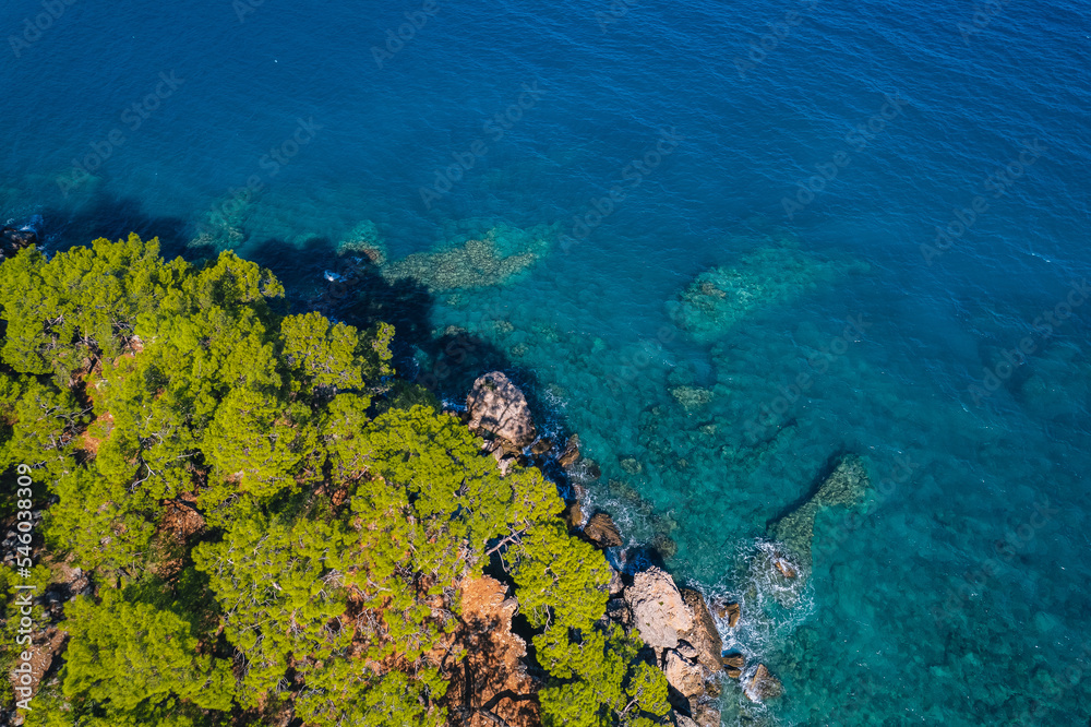 Fototapeta premium Aerial top view of clear blue water sea, rocks and forest at sunset in summer Turkey