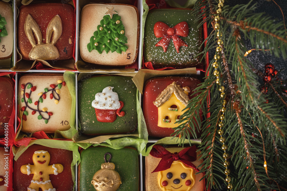 Delicious Christmas cookies set in a gift box. Advent calendar to count the days in anticipation of Christmas. Gingerbread cookies with festive red and green icing on the Christmas background