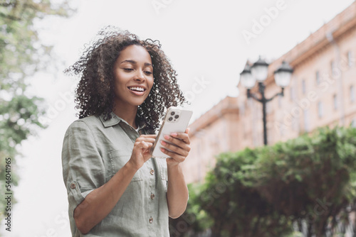 Young beautiful woman using smartphone in a city. Smiling student girl texting on mobile phone outdoor. Modern lifestyle  connection  casual business concept