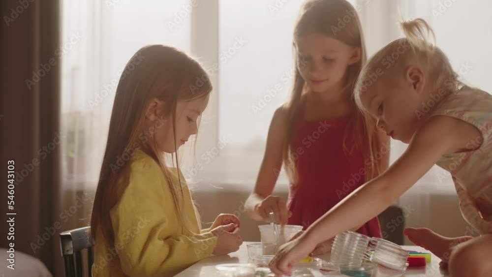 Three girls mixing ingredients together to make slime. Family, hobbies. Chemistry experiments, kids have fun learning Three girls mixing ingredients together to make slime. Family, hobbies. Chemistry experiments, kids have fun learning