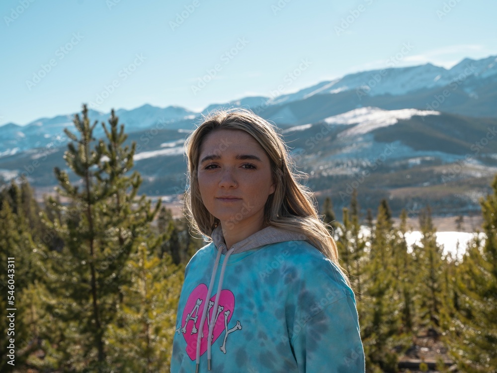 Charming Caucasian blonde young girl posing against the mountain background