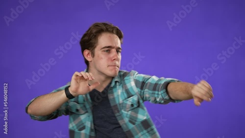 Portrait of smiling, dancing, grooving young man 20s, enjoying music. Handsome guy surprised isolated on solid purple background. photo