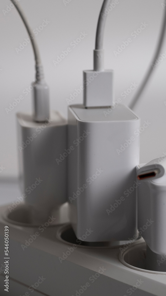 Many chargers are connected to an electrical outlet on a white background.