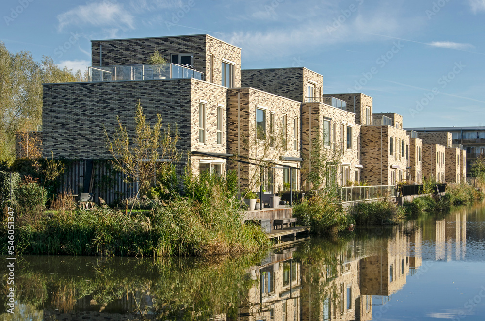 Utrecht, The Netherlands, November 13, 2022: brick cubist houses with wooden terraces reflecting in the adjacent pond in Leidsche Rijn neighbourhood