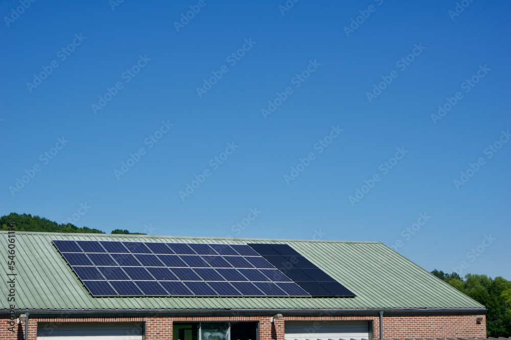 House with solar panels covering its tiled roof under a clear blue sky on a sunny day