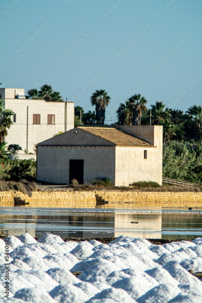Vertical shot of a white building on the shore in the salt evaporation pond. Marsala, Sicily, Italy.