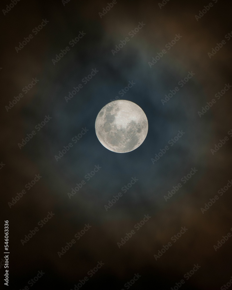 Vertical shot of a bright full moon isolated on the black cloudy sky background Vertical shot of a bright full moon isolated on the black cloudy sky background