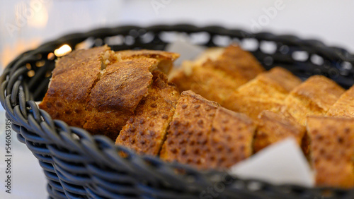A loaf of white bread cut into slices and arranged in a black basket. 