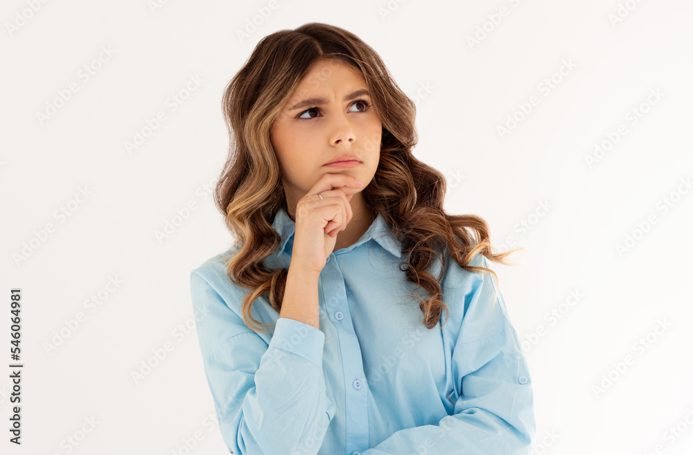 Thoughtful woman keeps hand on chin looks pensively above dressed in casual blue shirt poses against white background blank copy space for your advertising content thinks about future Thoughtful woman keeps hand on chin looks pensively above dressed in casual blue shirt poses against white background blank copy space for your advertising content thinks about future