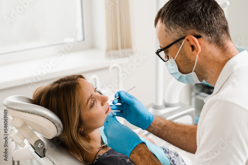 Dentist examines teeth of woman for treatment of toothache. Pain in teeth. Consultation with dentist in dentistry.