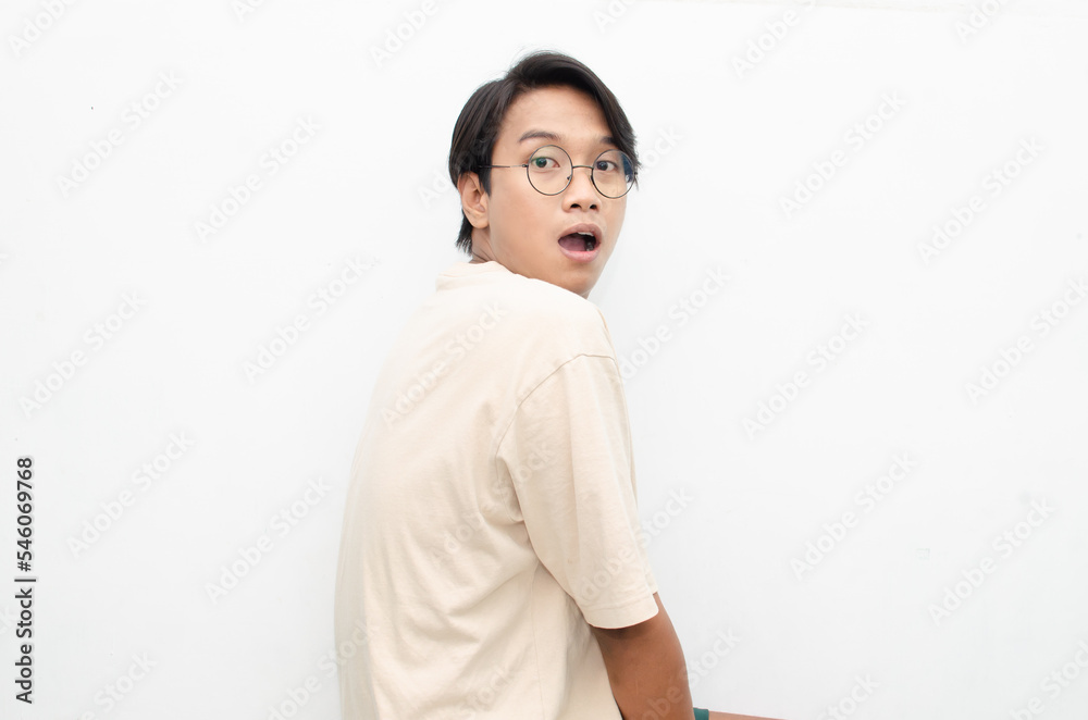 Asian young man wearing casual beige tshirt surprised, amazed, wow shocked raising arms gesturing victory and yes gesture Asian young man wearing casual beige tshirt surprised, amazed, wow shocked raising arms gesturing victory and yes gesture