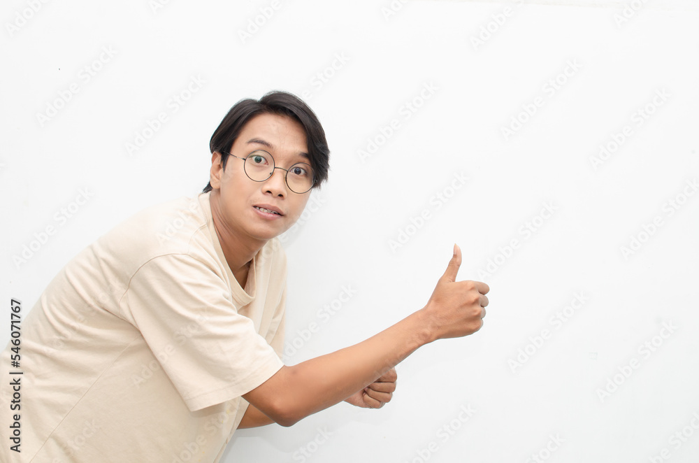 handsome attractive Asian man smiling happily and giving thumbs up as compliment isolated over white background. man giving approval and compliment by gesturing thumbs up. handsome attractive Asian man smiling happily and giving thumbs up as compliment isolated over white background. man giving approval and compliment by gesturing thumbs up.