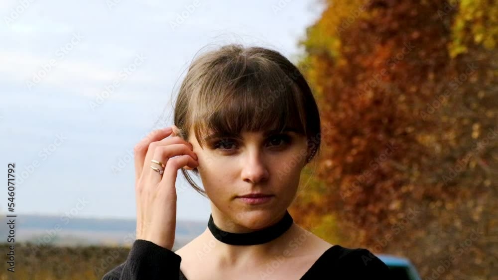A beautiful young girl straightens her hair against the background of the autumn forest A beautiful young girl straightens her hair against the background of the autumn forest