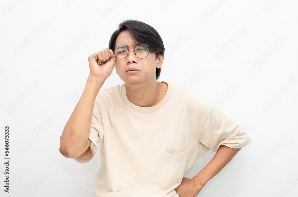 Young Asian man wearing glasses and beige tshirt with crying face expression isolated over white background. Crying face expression of Young Asian man with hand gesture. Young Asian man wearing glasses and beige tshirt with crying face expression isolated over white background. Crying face expression of Young Asian man with hand gesture.