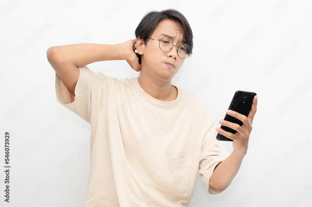 asian young man in casual beige tshirt holding phone with sad, crying, dissapointed expression. bad news from phone concept. asian young man in casual beige tshirt holding phone with sad, crying, dissapointed expression. bad news from phone concept.