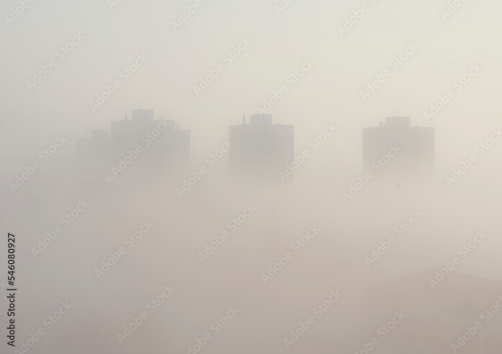 Fog over city with high buildings and urban architecture.  Outline and cityscape. Morning in the town with fog. 