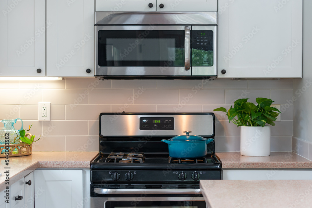 Kitchen detail of gas stove with blue soup pot and microwave above