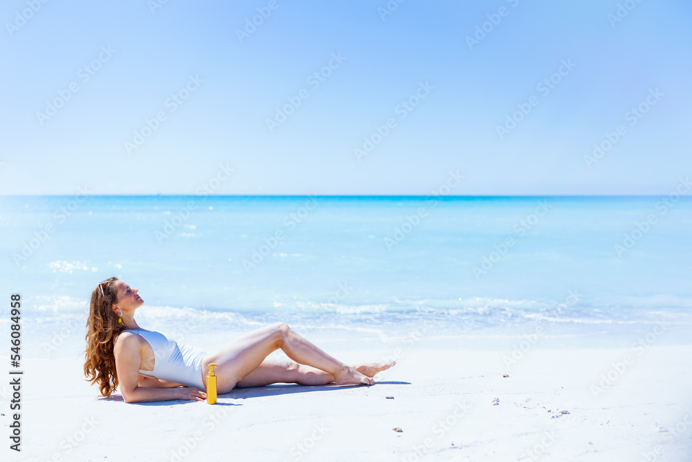 relaxed modern woman in white swimwear laying at beach
