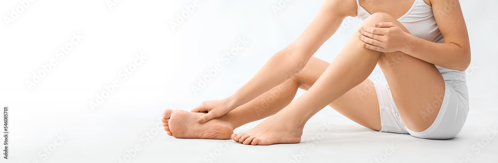 Young woman making foot massage on light background with space for text Young woman making foot massage on light background with space for text