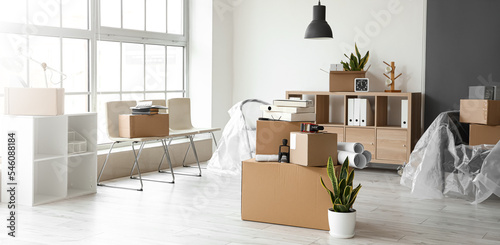 Cardboard boxes with belongings in interior of office on moving day