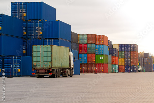 Truck while loading in logistic shipping yard with cargo container. Forklift truck handling truck. Logistic import export concept. Loading and unloading of containers in the port.