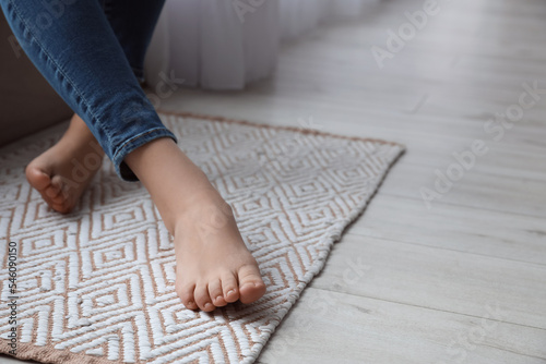 Female bare feet on rug, closeup