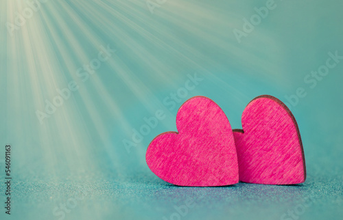 Pink hearts on a turqouise background with sunbeams, valentine greeting card, mothers day and birthday wishes, love symbol