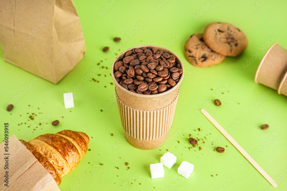 Paper cup of coffee beans on green background - obrazy, fototapety, plakaty 
