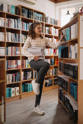Obraz na plátně Teen girl among a pile of books