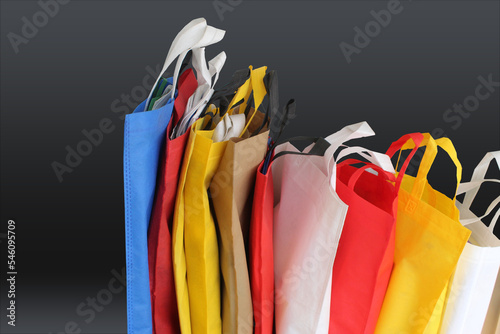 Beautiful Non Woven grocery shopping bags with black background. Assorted Colors Eco friendly bags with copy space for text. pile of textured and porous polypropylene material. partially sighted image photo