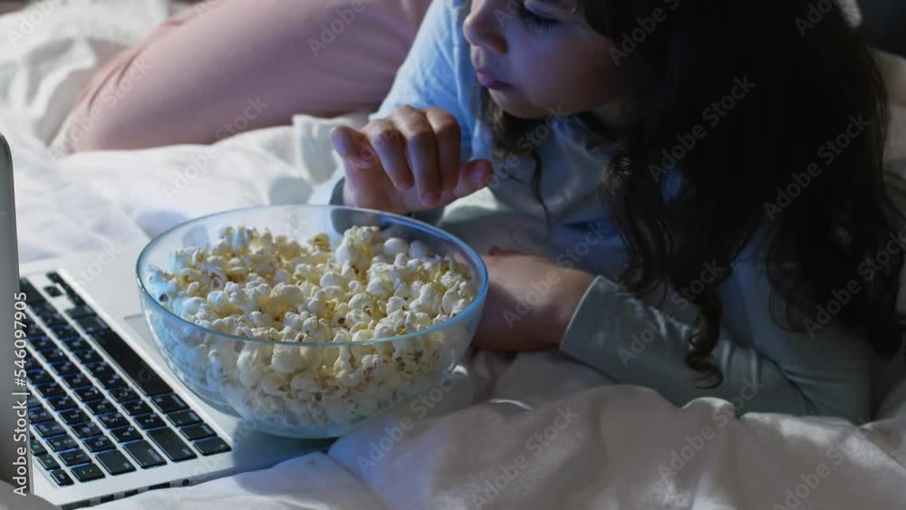 A child eats popcorn while watching a movie. A child eats popcorn while watching a movie.
