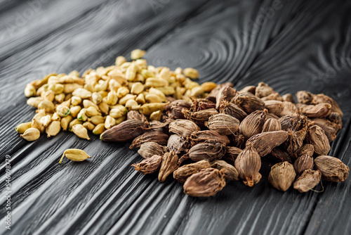 a barrel of dried black cardamom on a black wooden rustic background