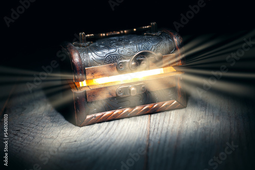 Obraz na płótnie Glowing bright rays of light from an old, open wooden dark brown treasure chest,