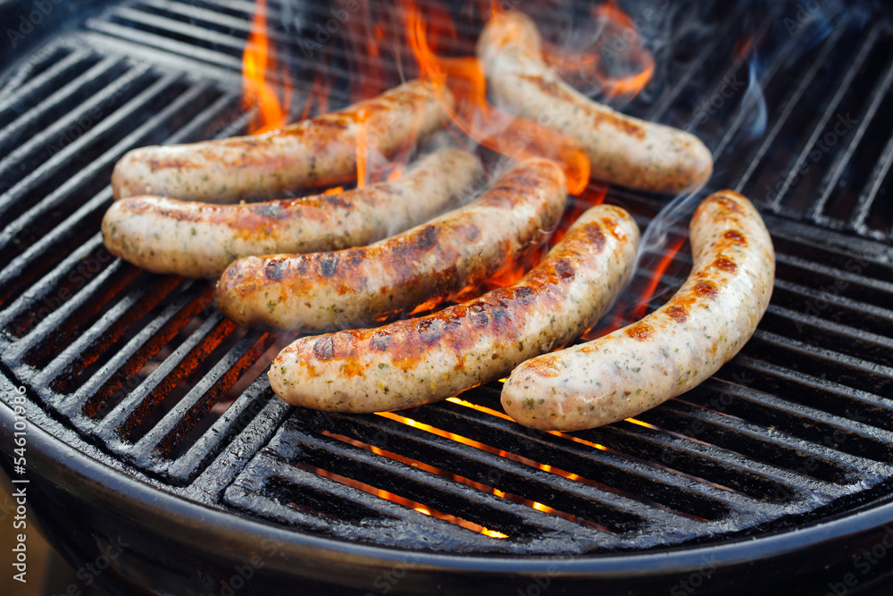 Barbecue Allgäu bratwurst offered as close-up on a charcoal grill with fire and smoke Barbecue Allgäu bratwurst offered as close-up on a charcoal grill with fire and smoke