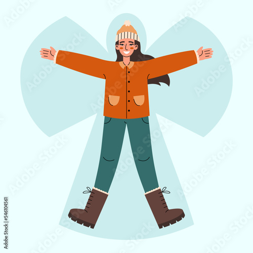 Young woman lying in snow on back and moving arms and legs. Smiling girl making snow angel. Winter entertainments concept.
