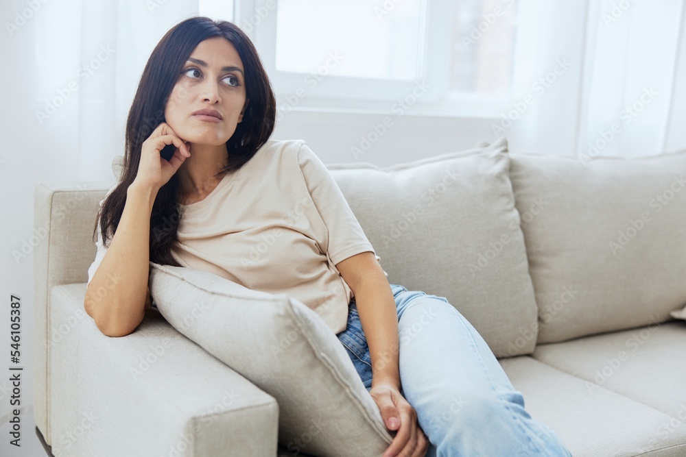 Headache woman sits at home on the couch and touches her head with her hands massage of the temples, high fever in case of illness, migraine Headache woman sits at home on the couch and touches her head with her hands massage of the temples, high fever in case of illness, migraine