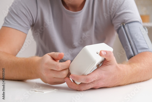 A man measures blood pressure with a white electric tonometer lying on a white table. Measurement of pressure and pulse. The concept of a healthy lifestyle.