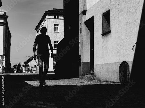 Fototapeta Naklejka Na Ścianę i Meble -  silhouette of the man on the street of small town, people on the streets