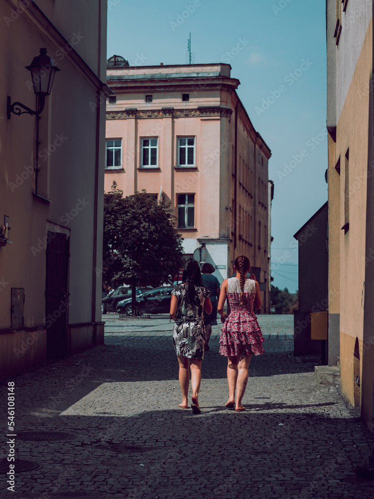 women in dresses lit by the sun, streets of old town