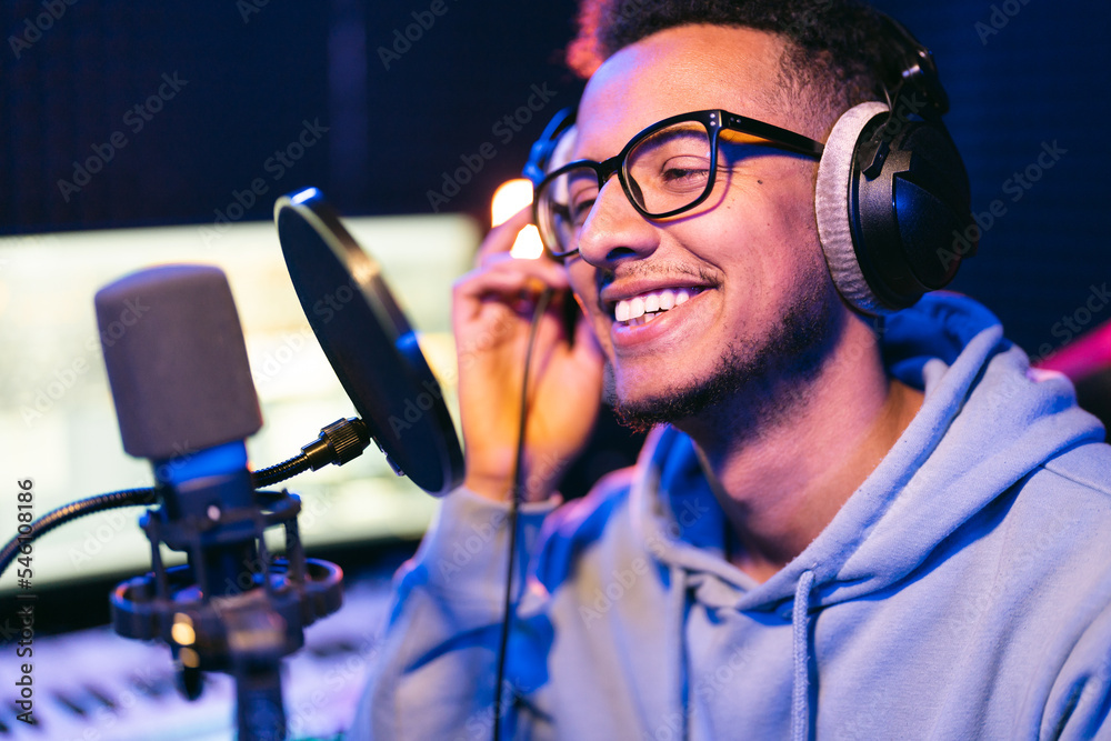 Male vocal artist, singer, podcaster with curly hair, headphones in sound studio recording new melody or album. Male vocal artist, singer, podcaster with curly hair, headphones in sound studio recording new melody or album.