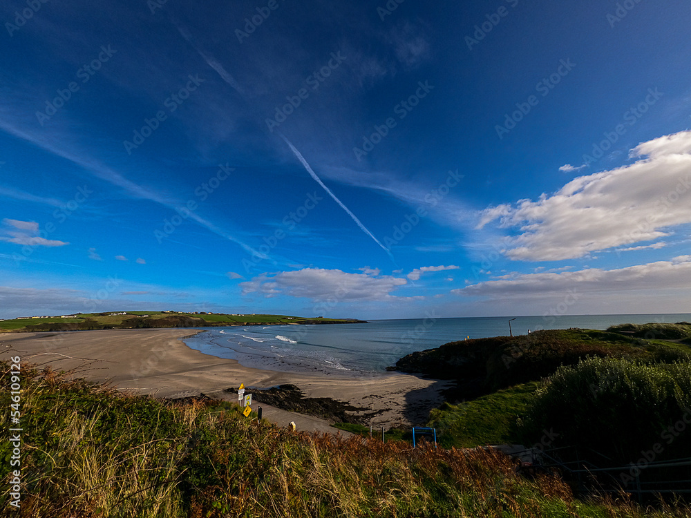 Panoramic view of Inchydoney Beach, on a sunny day with clouds in the sky.