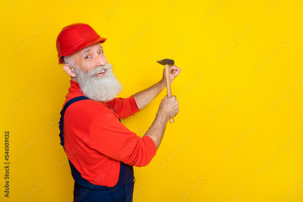 Photo of professional retired pensioner workman architect hammer nail into wall isolated on bright color background