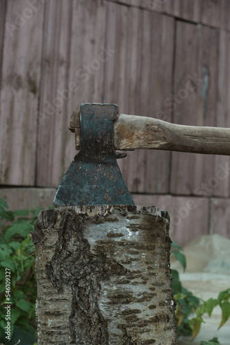 Old rusty axe with wooden handle stuck in the stump Large ax in hand